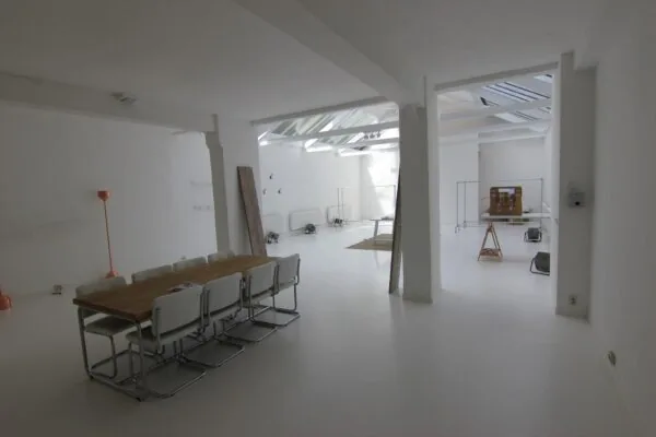 Licht en minimalistisch ingericht interieur in een ruimte aan de Graaf Florisstraat met een houten tafel, witte stoelen en een glazen dak.